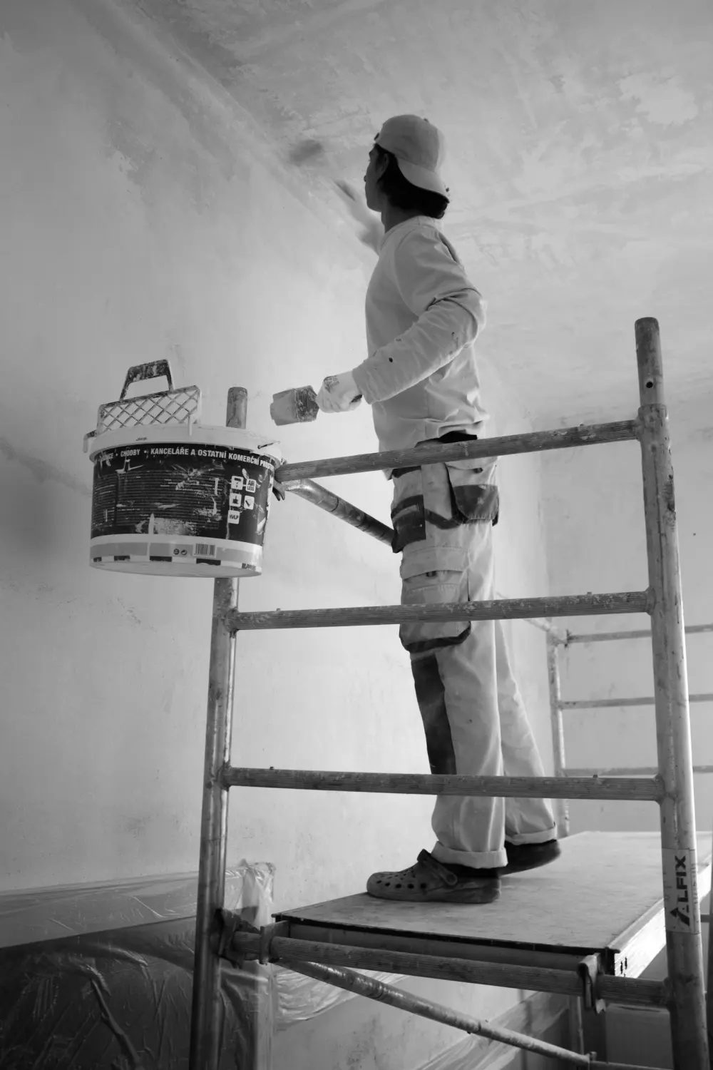 Imbianchino su un trabattello che dipinge il soffitto di una stanza